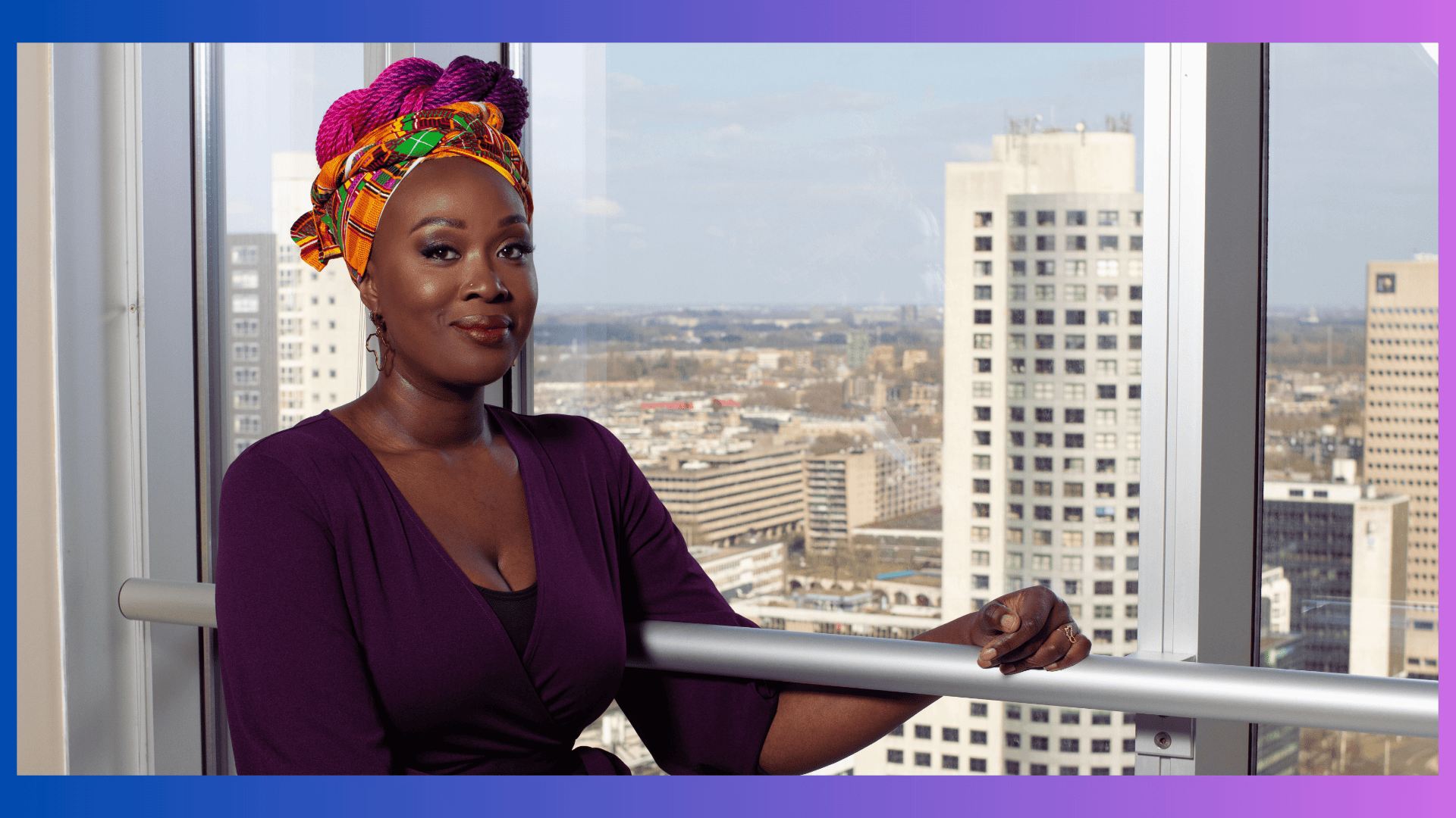 Vivian Acquah, a woman in a purple dress and an African head wrap with ombre purple blue braids leaning on a railing